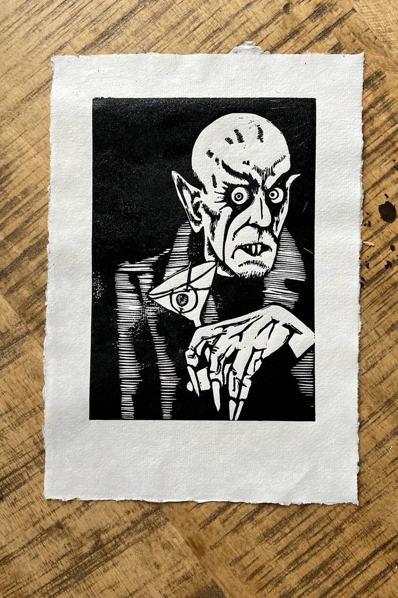 Schwarz/Weiss Linoldruck. Motiv: Nosferatu mit einem Glas Martiniin der Hand. Nosferatu trinkt diesen natürlich mit einem aufgespiessten Augapfel, anstelle einer klassischen Olive :). Der Druck ist handgezeichnet, handgedruckt und signiert.