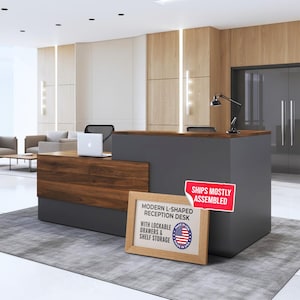 May include: Modern L-shaped reception desk with a dark gray base and a wooden top. The desk has lockable drawers and shelf storage. The image also shows a laptop and a framed sign that says "Made in USA".