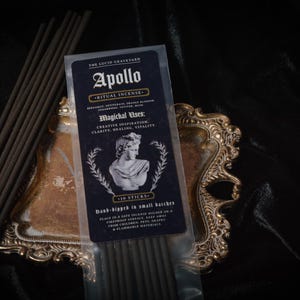 May include: A package of Apollo ritual incense with 10 sticks, featuring a bust of Apollo and the text "Magichal Uses: Creative Inspiration, Clarity, Healing, Vitality." The incense is on a decorative gold-colored tray.