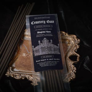 May include: A package of "Cemetery Gate" ritual incense sticks with text that reads "Magical Uses: Protection, Warding, Shielding, Boundaries." The incense is in a clear plastic wrapper, with a black label and a gold decorative tray.