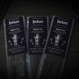 May include: Three packages of Hekate ritual incense. Each package has a black label with white text, including "Hekate" and "Magichal Uses." The labels feature an illustration of a goddess and keys. Each package contains 10 sticks.
