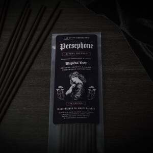 May include: A packet of Persephone ritual incense sticks. The black label reads "The Lucid Graveyard" and "Persephone Ritual Incense." The label also includes the text "Magichal Uses: Renewal, Growth, Balance, Underworld Connection." The package contains 10 sticks.
