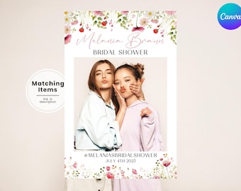 May include: A white photo booth backdrop with a floral border and the text "Melania Braun Bridal Shower" and "#MELANIASBRIDALSHOWER JULY 4TH 2025".