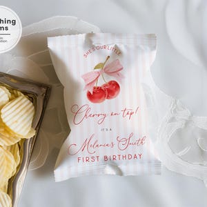 Może przedstawiać: Biało-różowa torba na chipsy w paski z akwarelowym wzorem wiśni i napisem "Cherry on top! It's a [Name] First Birthday". Torba ma również napis "She's our little". Srebrna taca z chipsami znajduje się na zdjęciu.
