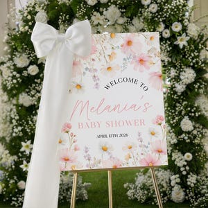 Set of printable baby shower kit featuring invitations, envelopes, and tags in soft pink with hand-drawn cosmos wildflowers, elegant gold script, and green foliage accents on a light blush background.
