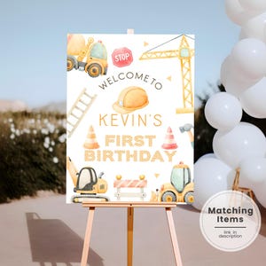 Könnte beinhalten: Ein rechteckiges Geburtstagsschild auf einer Holzstaffelei mit Aquarell-Baustellenillustrationen wie Betonmischer, Kran, Leiter, Stoppschild, Bauhelm, Verkehrskegeln und Baggern mit dem Text WELCOME TO KEVIN'S FIRST BIRTHDAY.