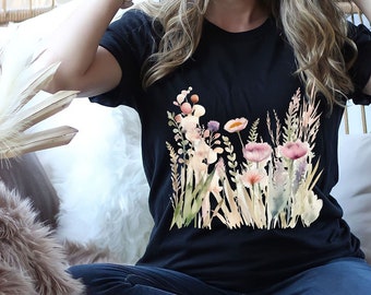 May include: A woman wearing a black t-shirt with a floral print and a brown hat sits in a wicker chair. She is wearing blue jeans and brown leopard print shoes.