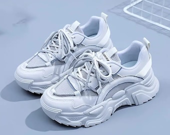 May include: White sneakers with a chunky platform sole and mesh panels. The laces are white and the shoes have a sporty look.