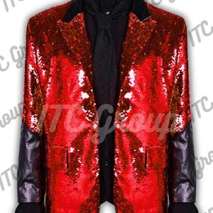 May include: A red sequined blazer with black leather sleeves and a black collar. The jacket is paired with a black shirt and tie. The blazer has two front pockets and a two-button closure. The overall style is a formal, stage-ready look.