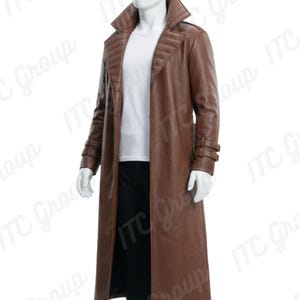 Può includere: Un trench coat lungo in pelle marrone con ampio colletto e vestibilità lunga e su misura. Il cappotto presenta un design a coste sulle spalle e un dettaglio cintura sulle maniche. Il manichino indossa una camicia bianca e pantaloni neri.