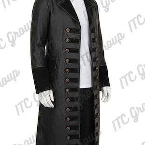 Puede incluir: Abrigo largo negro con múltiples filas de botones color bronce y detalles de terciopelo negro. El abrigo tiene un cuello alto y mangas largas con puños negros. Se ve una camisa blanca debajo. Estilo clásico.