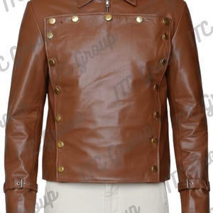 Puede incluir: Chaqueta de cuero marrón con cremallera y cuello. La chaqueta presenta botones dorados y hebillas en las mangas. La chaqueta se lleva sobre una camisa blanca.