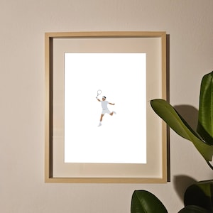 May include: A framed print of a tennis player in mid-air, swinging a racket. The player is wearing a white uniform and white shoes. The background is white.