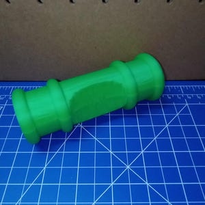 May include: A bright green plastic pipe with rounded ends. The pipe is about 10 inches long and 2 inches in diameter.