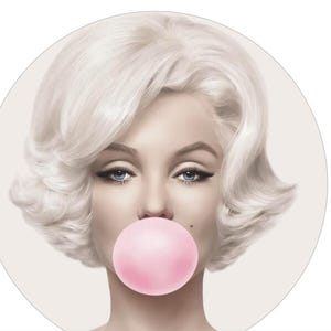 May include: A black and white portrait of a woman with blonde hair blowing a pink bubble. The woman is wearing lipstick and has a neutral expression.