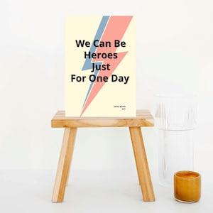 May include: A yellow poster with a pink and blue lightning bolt graphic. The poster has the text "We Can Be Heroes Just For One Day" and the text "David Bowie 1977" at the bottom.