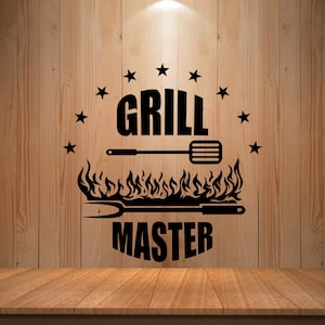 May include: Black "Grill Master" wall art with a spatula, fork, flames, and stars. The text is in a bold, sans-serif font. The design is set against a wooden background, with a wooden table in the foreground.