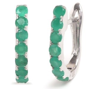 May include: A pair of silver hoop earrings featuring a row of five round, vibrant green gemstones set along the front curve of each hoop. The earrings have a polished metallic finish and a secure hinged closure mechanism for comfortable wear.