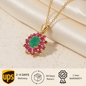 Può includere: Una collana in oro con un ciondolo caratterizzato da una pietra preziosa ovale verde centrale circondata da un alone di piccole pietre rosse rotonde. Il ciondolo è fissato a una sottile catenina d'oro dal classico design floreale vivace.