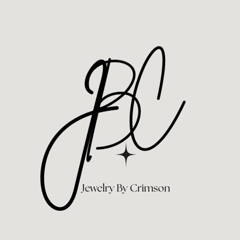 Puede incluir: El logotipo de "Jewelry By Crimson" presenta las letras "J", "B" y "C" entrelazadas en negro. Una peque&ntilde;a estrella de cuatro puntas se encuentra debajo de las letras, y el nombre de la marca est&aacute; en una fuente sans-serif simple.