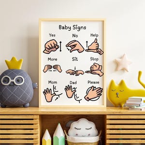 A framed baby sign language poster displayed on a wooden shelf between plush toys.