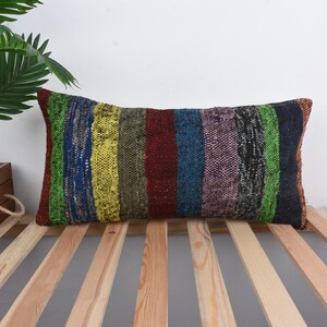 Könnte beinhalten: Ein farbenfrohes, gestreiftes Kissen mit gewebter Struktur. Das Kissen ist aus recycelten Materialien hergestellt und perfekt, um Ihrem Zuhause einen Hauch von Boho-Stil zu verleihen.