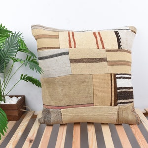 Op de afbeelding: Een beige en bruin patchwork kussen met een rechthoekige vorm. Het kussen is gemaakt van verschillende stoffen en heeft een rustieke, vintage uitstraling.