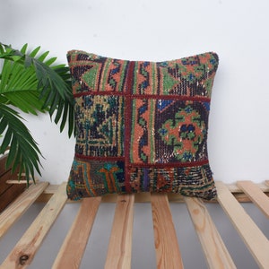 May include: A colorful square throw pillow with a patchwork design featuring geometric patterns in shades of red, orange, green, blue, and brown.