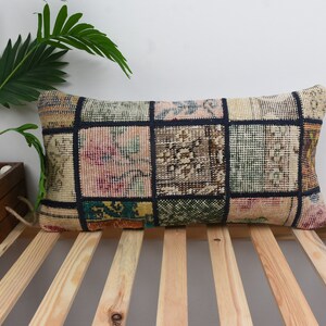 Könnte beinhalten: Ein rechteckiges Kissen mit Patchwork-Muster in verschiedenen Farben und Mustern. Das Kissen ist aus weichem, gewebtem Stoff gefertigt und hat einen schwarzen Rand um jedes Quadrat.