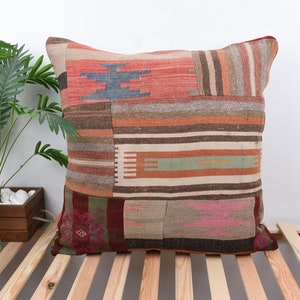 May include: A colorful patchwork pillow with a variety of stripes and patterns in shades of red, orange, brown, and beige. The pillow is made from recycled materials and has a unique, handmade look.