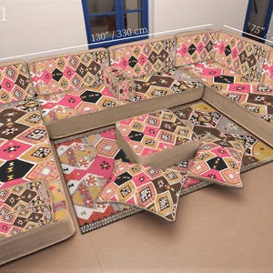 May include: A sectional sofa set with a geometric pattern in pink, brown, black, and beige. The set includes multiple pieces, with dimensions of 130 inches/330 cm, 75 inches/190 cm, and 28 inches/70 cm. The set is arranged on a neutral surface.