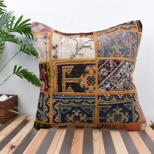 Könnte beinhalten: Ein quadratisches Patchwork-Kissen mit verschiedenen bunten Mustern und Texturen. Das Kissen ist aus recycelten Materialien hergestellt und hat einen einzigartigen, bohemischen Stil.