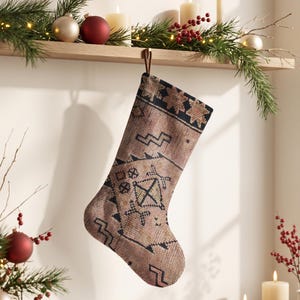 Könnte beinhalten: Ein Weihnachtsstrumpf aus braunem und beigem Webstoff mit einem dunkelblauen geometrischen Muster. Der Strumpf hat eine einfache braune Aufhängeschlaufe an der Oberseite und zeigt eine texturierte, teppichartige Optik mit verschiedenen eckigen Formen.