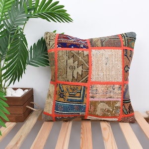 May include: A patchwork cushion cover featuring a mix of colours and patterns, including orange, brown, beige, and blue. The cushion cover is crafted from recycled materials and has a distinctive, handmade appearance.