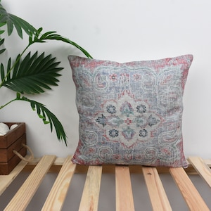 May include: A decorative throw pillow with a pink, blue, and white patterned design. The pillow is made of a soft, textured fabric and has a square shape.