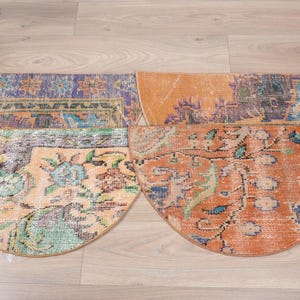 May include: Four half-circle rugs with a vintage, distressed look. The rugs are in shades of orange, blue, and green with floral patterns.