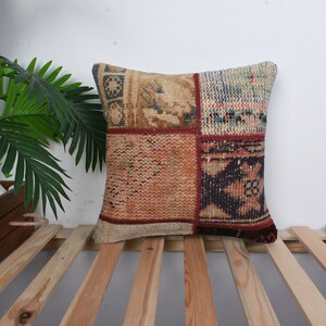 May include: A patchwork pillow cover with a variety of colors and patterns, including red, blue, and brown. The pillow cover is made of a woven fabric and has a fringed edge.