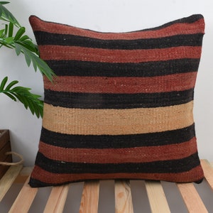 May include: A striped throw pillow with black, red, and beige stripes. The pillow is made of a woven fabric and has a soft, textured feel.