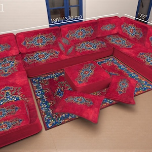 Könnte beinhalten: Ein rotes Ecksofa-Set mit aufwendigen blauen und goldenen Mustern. Das Set beinhaltet ein großes Sofa, Eckteile und Zierkissen. Die Abmessungen betragen 330 cm Länge, 190 cm Breite und 70 cm Tiefe.