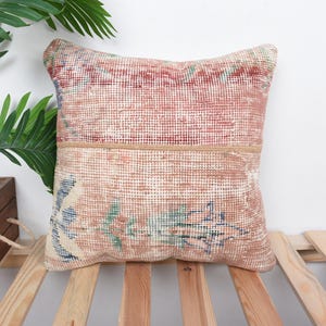 May include: A pink and cream throw pillow with a floral pattern. The pillow is made from a woven fabric and has a fringe border.