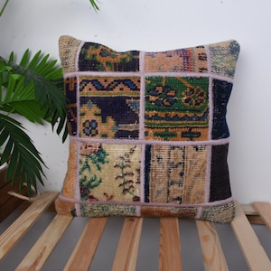 Op de afbeelding: Een patchwork kussenhoes met verschillende kleuren en patronen, waaronder blauw, groen en beige. De kussenhoes is gemaakt van een zachte, geweven stof en heeft een gefranst randje.