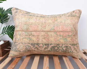 May include: A rectangular cushion with a floral pattern in shades of pink, green, and beige. The cushion is made of a soft, woven fabric and has a fringed edge.