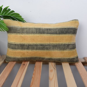 May include: A yellow and black striped throw pillow with a woven texture.