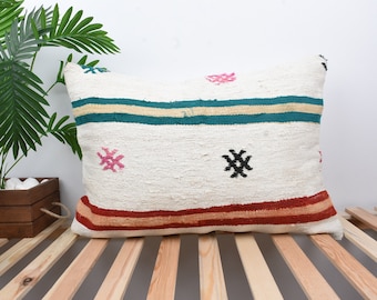 May include: White throw pillow with a colorful geometric pattern. The pattern includes teal, beige, red, and pink stripes, as well as black and pink embroidered designs.