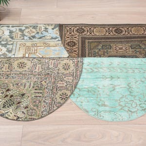 May include: Four half-circle rugs with different patterns and colours. The rugs are arranged in a circle with the top rug being a light blue and brown rug with a floral pattern. The rug below it is a brown and green rug with a floral pattern. The rug below that is a light blue rug with a faded floral pattern. The bottom rug is a light green rug with a faded floral pattern.