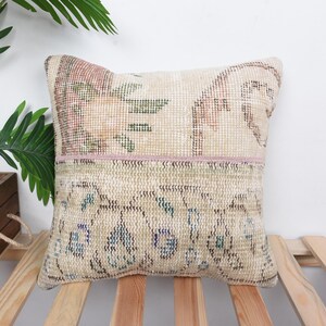 May include: A decorative throw pillow with a floral pattern in shades of pink, brown, and green. The pillow has a pink trim and is made from a woven fabric.