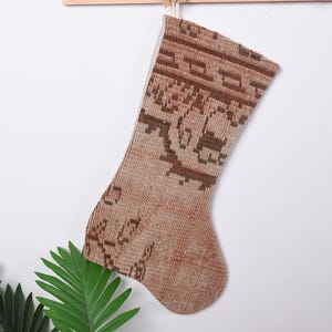 Op de afbeelding: Een bruine en beige kerstsok van geweven stof.