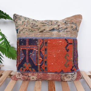May include: A square throw pillow with a patchwork design. The pillow is made of different fabrics with various colors and patterns, including red, blue, and beige. The pillow is perfect for adding a touch of bohemian style to any room.