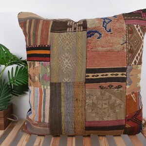 May include: A patchwork pillow with a variety of colors and patterns. The pillow features rectangular patches in shades of brown, beige, orange, and blue. The design includes stripes, geometric shapes, and textured fabrics. A decorative accent for a living room or bedroom.