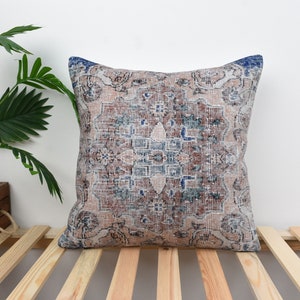 Könnte beinhalten: Ein dekoratives Kissen mit einem Vintage-Blumenmuster in Blau-, Braun- und Weißtönen. Das Kissen ist aus einem weichen, gewebten Stoff gefertigt und hat eine quadratische Form.